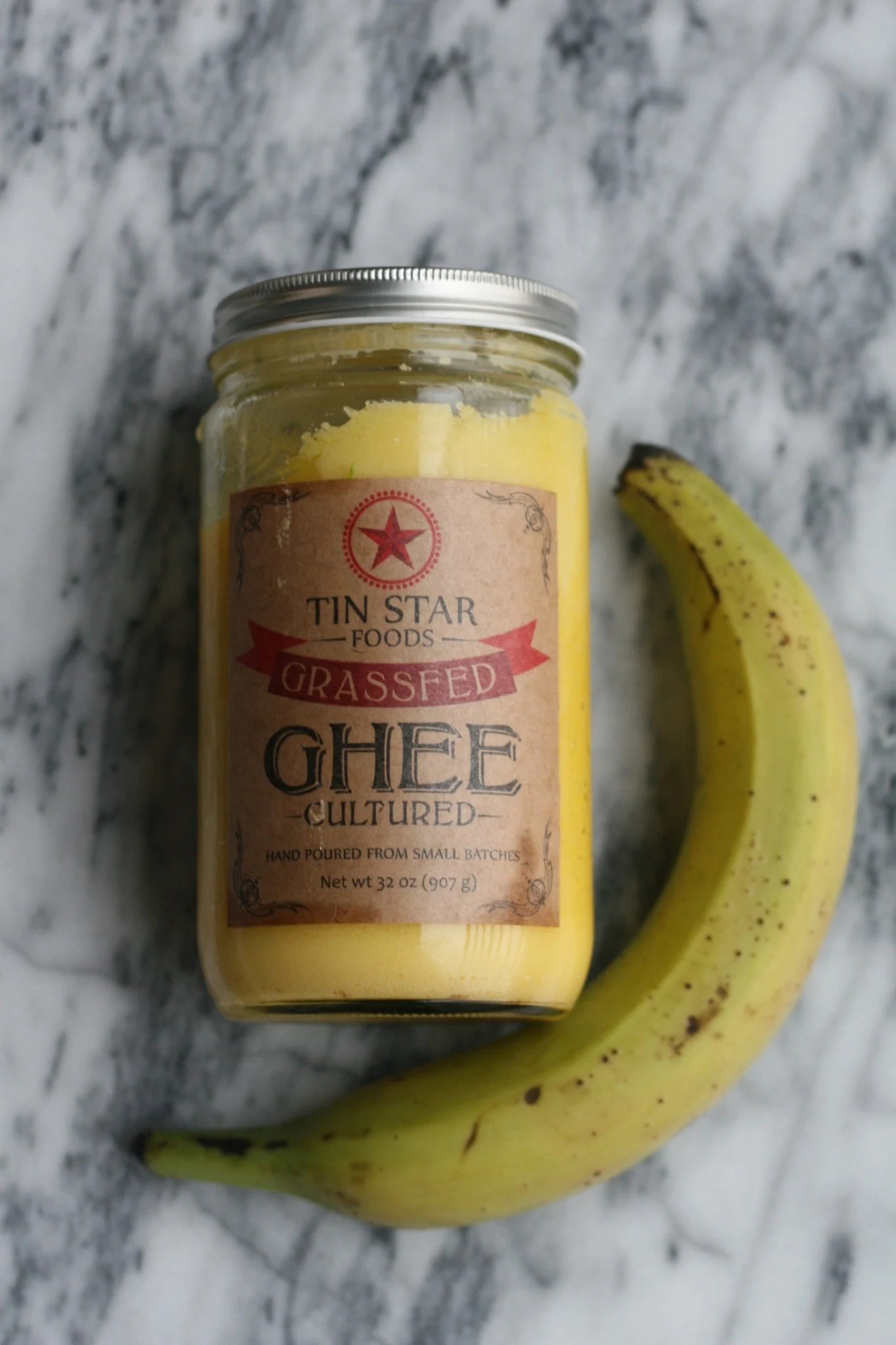 A jar of ghee and a banana on a counter.