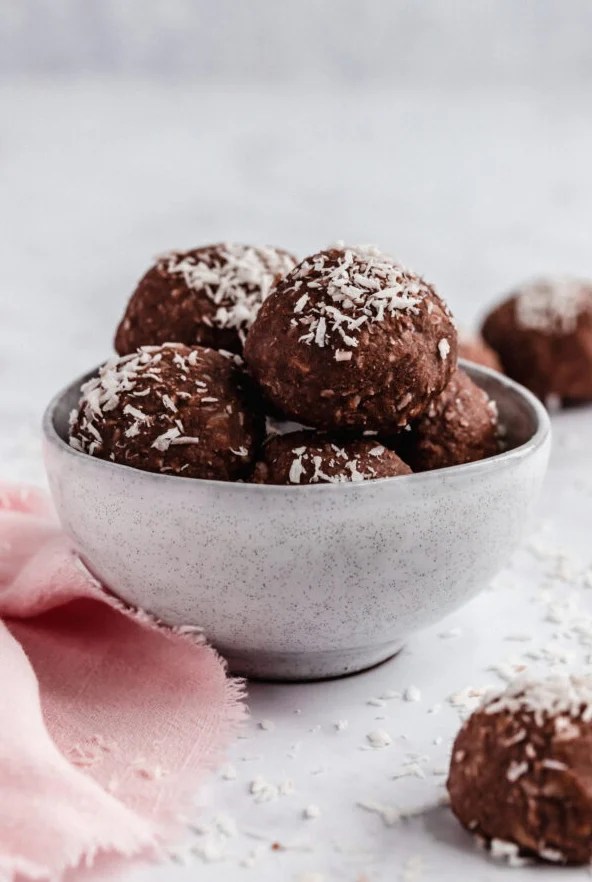A white bowl filled with chocolate collagen protein bowls with coconut on top.