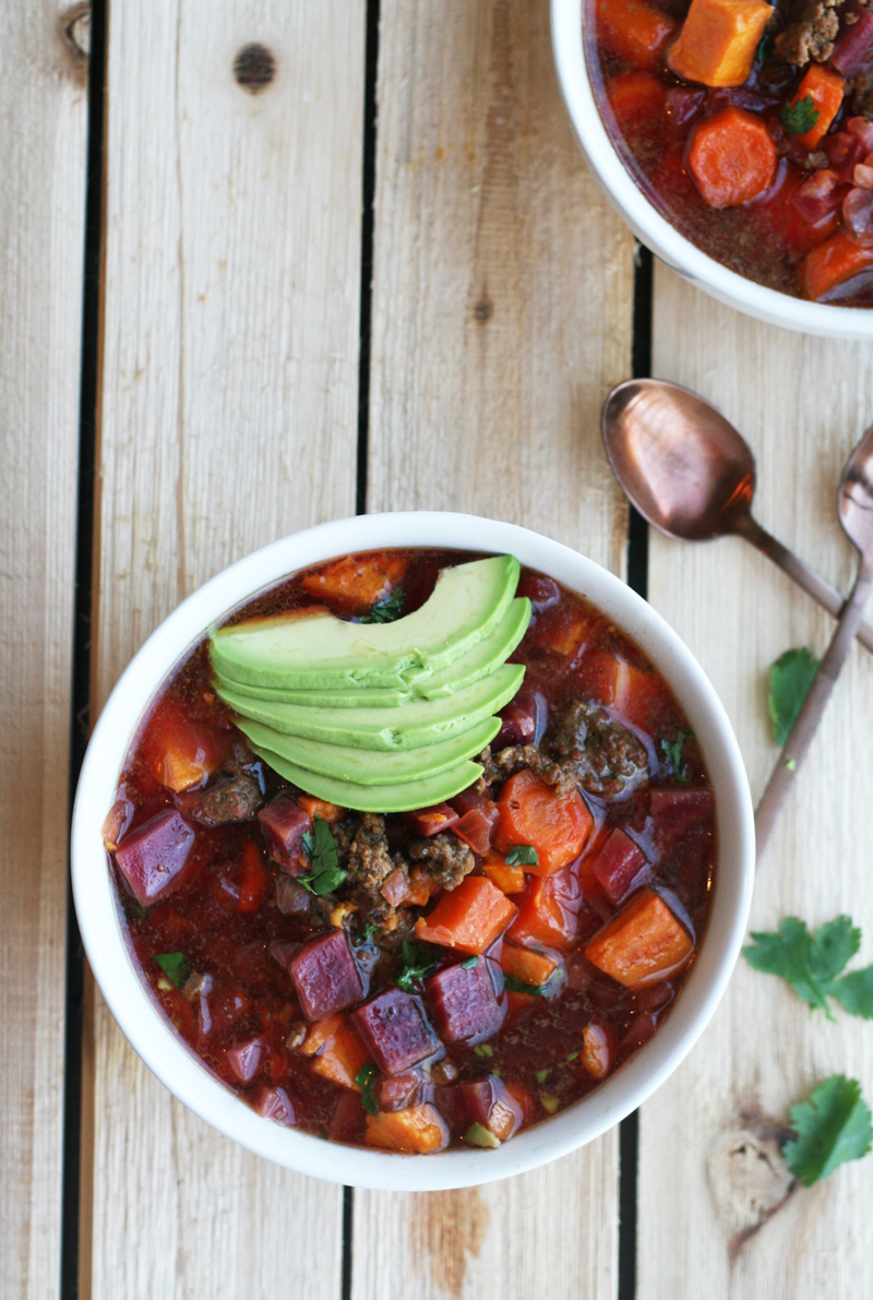 A bowl of chili with avocado on top.