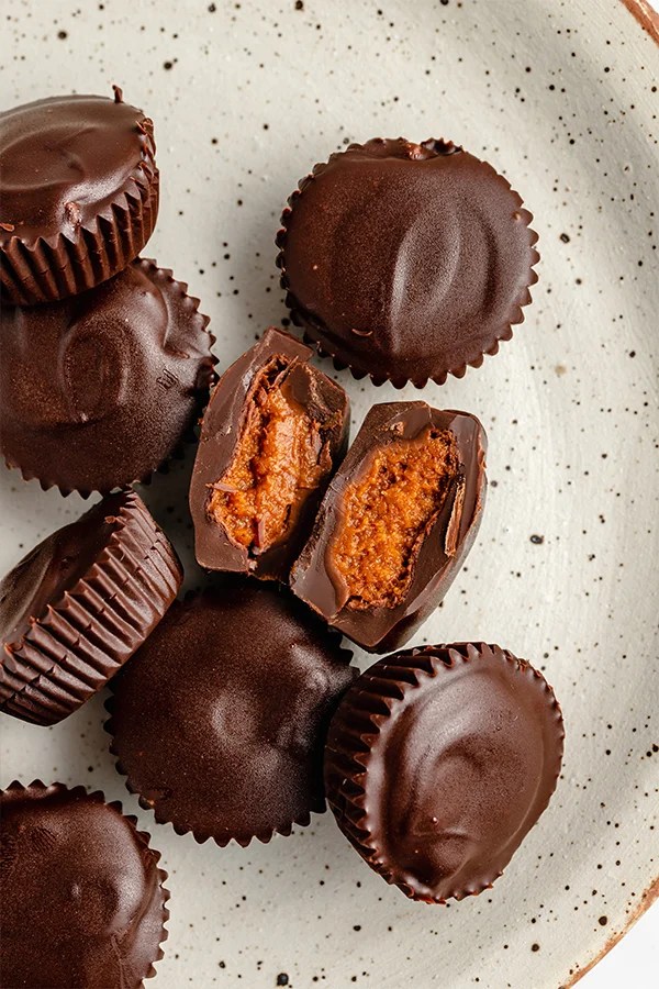 A speckled plate topped with many chocolate pumpkin butter cups.