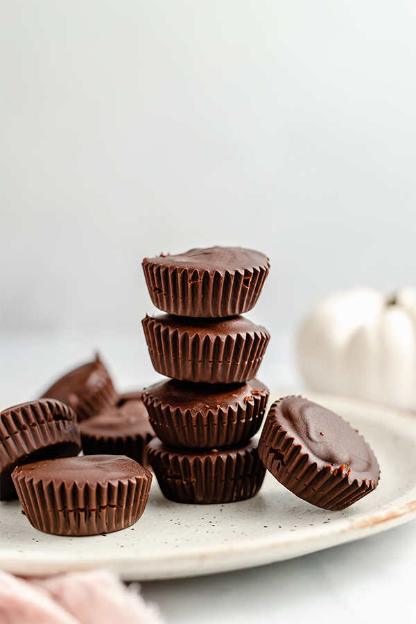 A speckled plate topped with many chocolate pumpkin butter cups.