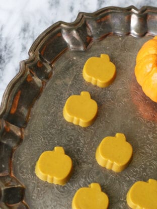 Turmeric gummies in a pumpkin shape on a brass platter.