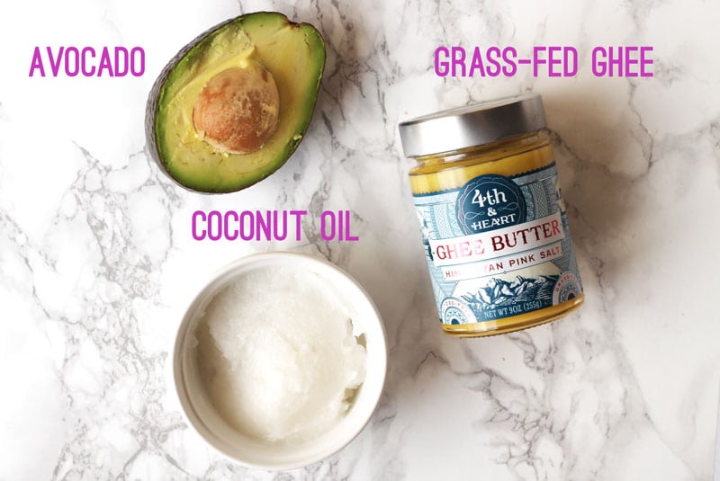 Coconut oil, avocado, and ghee on a marble background.