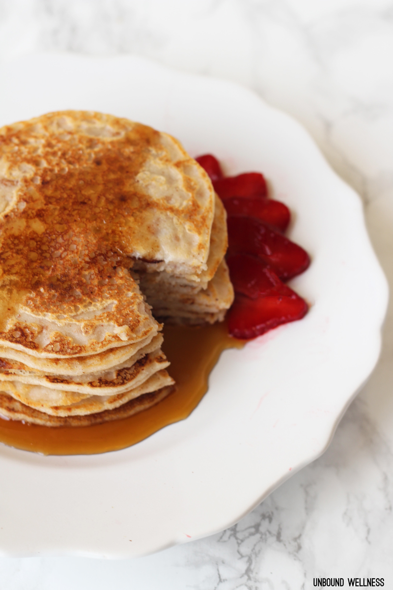 A stack of pancakes with strawberries and syrup.
