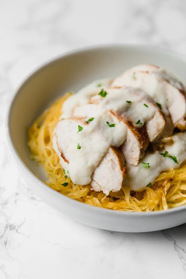 A white bowl with paleo spaghetti squash chicken alfredo in it.