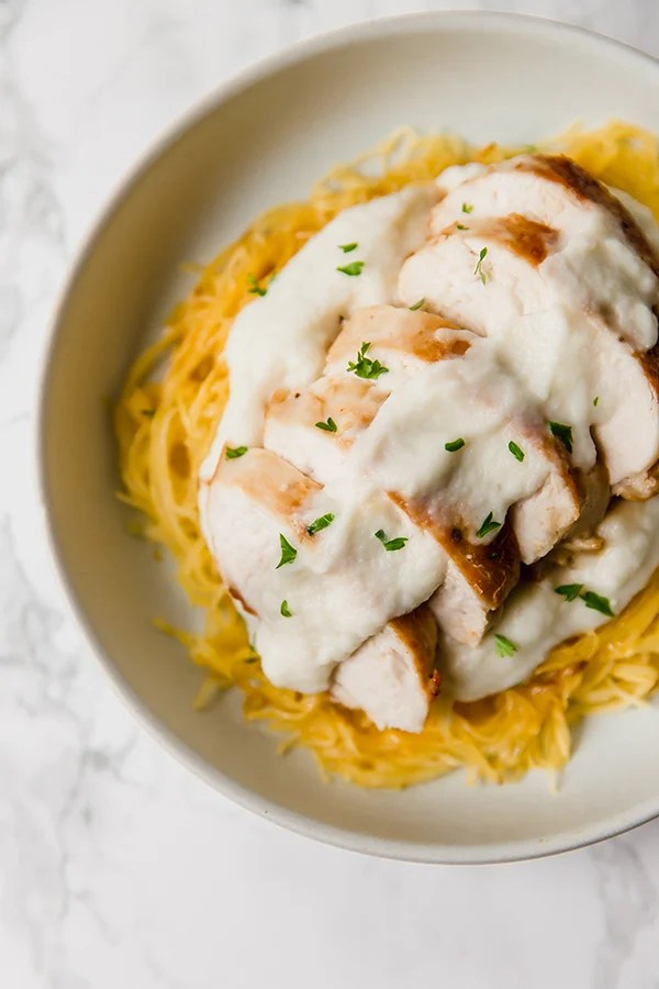 A white bowl filled with spaghetti squash chicken alfredo ready to be eaten.
