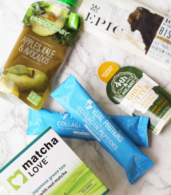 Matcha, two packets of collagen, a travel sized container of ghee, and an epic bar out on a marble background.