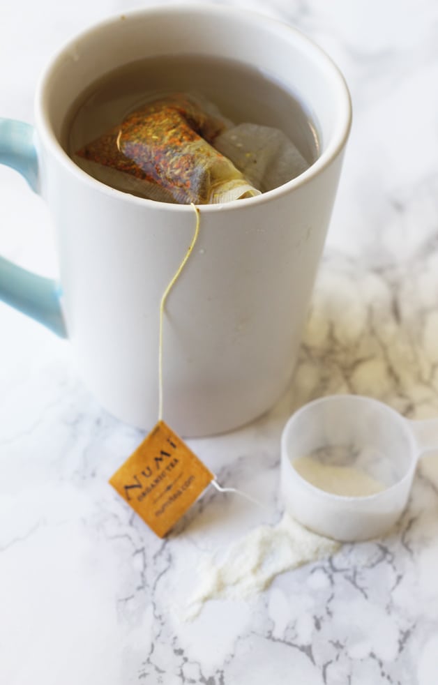 A mug of tea with a serving of collagen next to it.