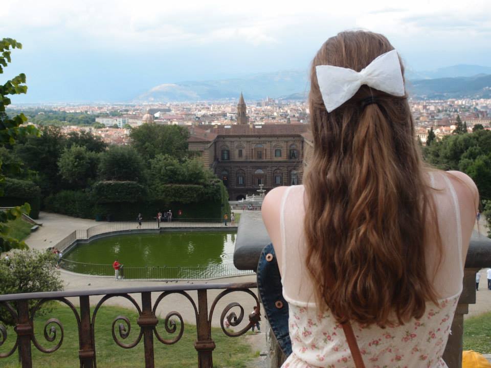 A shot of Michelle from the back overlooking a pond and a city.