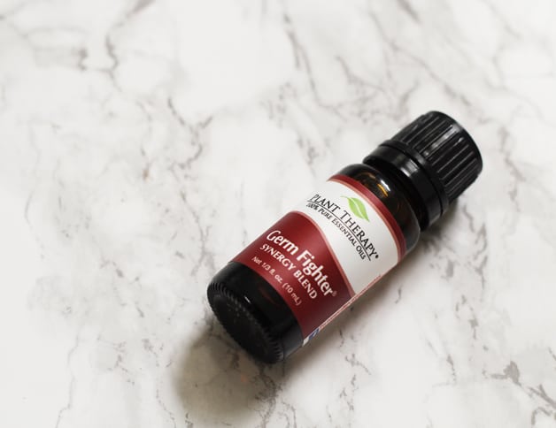 A small bottle of germ fighter blend lying on a counter.