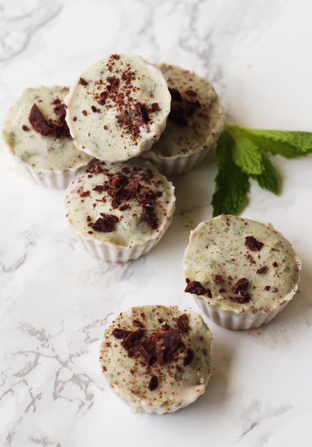 Several mint ice cream cups sitting on a counter with fresh mint.