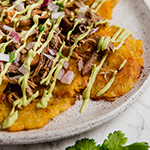 A white plate with tostone carnitas nachos on it.