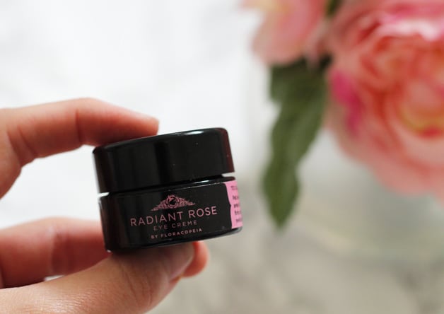 A hand holding a small container of radiant rose .