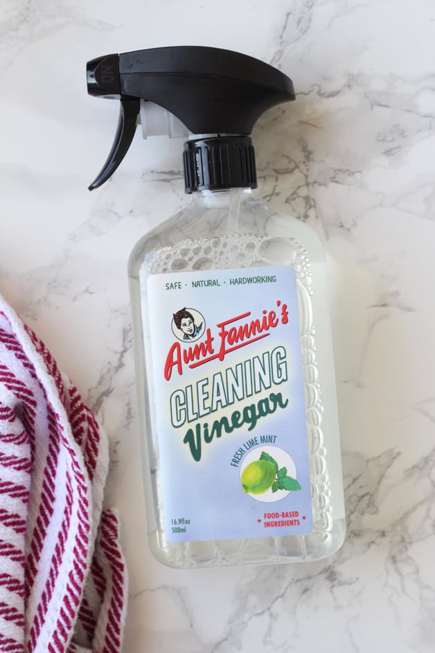 A shot of Aunt Fannie\'s Cleaning Vinegar in a spray bottle with a cleaning cloth next to it.