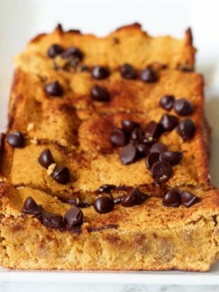 A loaf of pumpkin bread with chocolate chips on top sliced into slices.