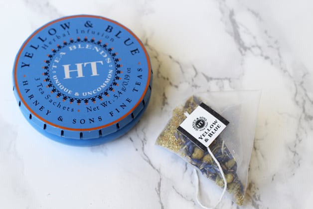 A tin of teablend with a tea bag next to it.