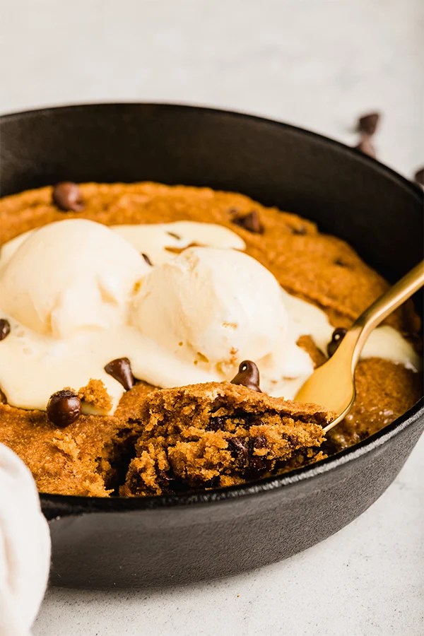 A close up of the pumpkin chocolate chip cookie skillet topped with ice cream.