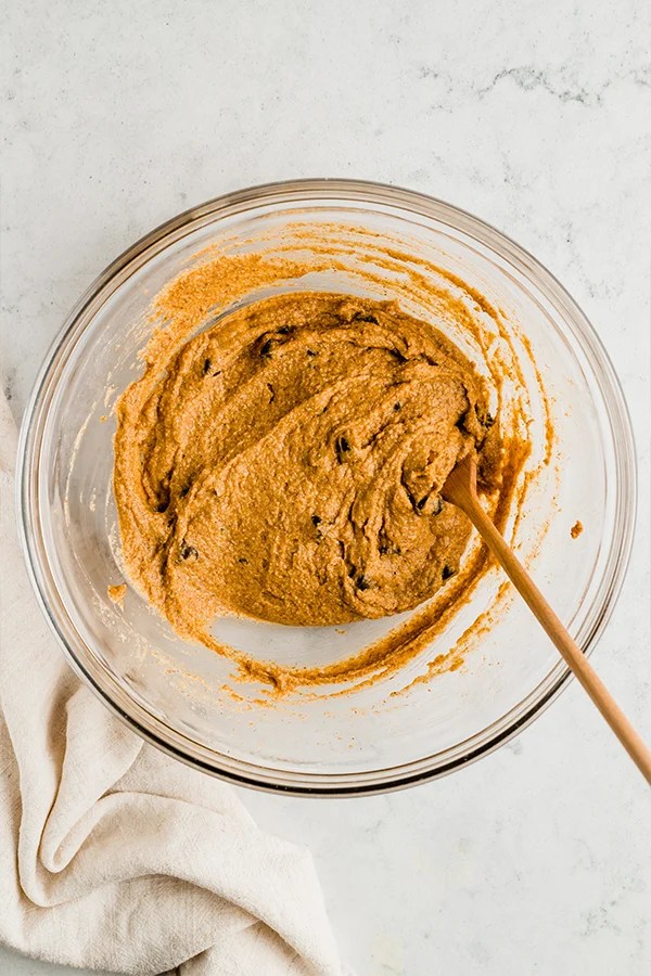 A bowl of pumpkin chocolate chip cookie skillet dough with a wooden spoon.