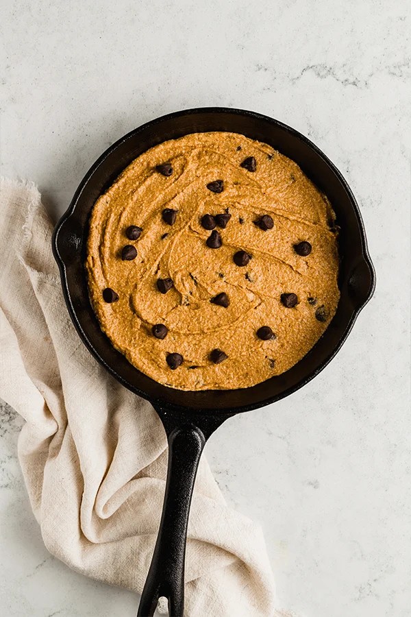 A cast iron skillet filled with pumpkin chocolate chip cookie skillet dough.