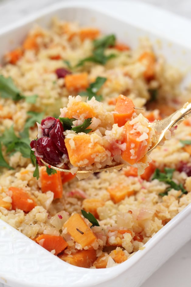 A container of paleo stuffing with a spoon taking a spoonful out.