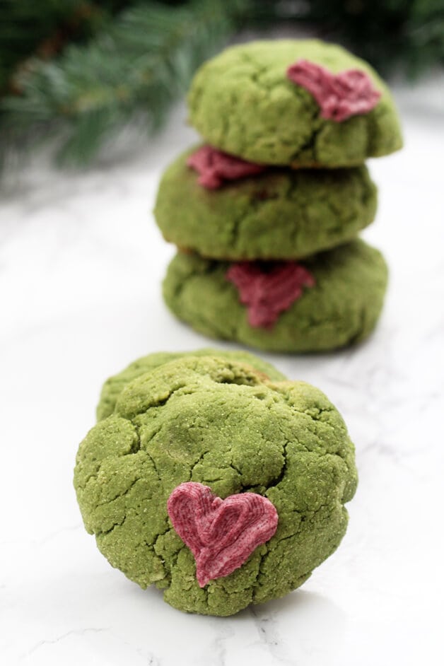 A grinch cookie in front of a stack of grinch cookies positioned behind it.