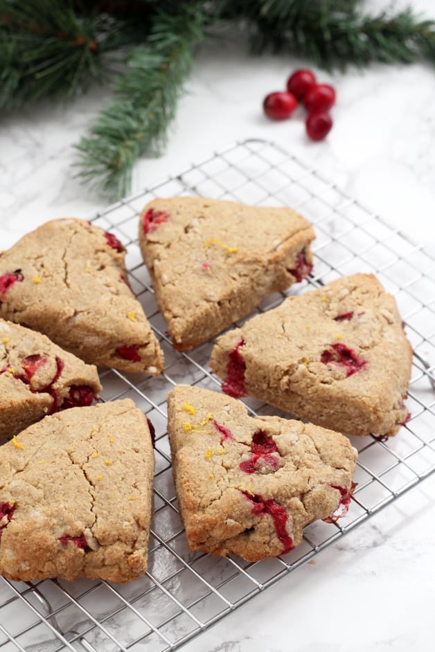 Six orange cranberry scones on a metal cooling rack after baking.