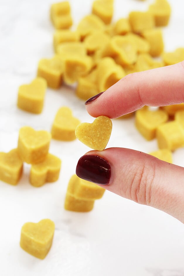A stack of turmeric chewables with a hand holding one turmeric chewable in it.