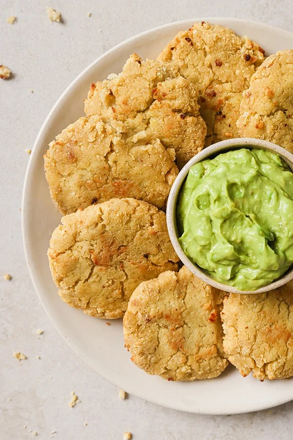 Cauliflower veggie nuggets around a bowl of guacamole.