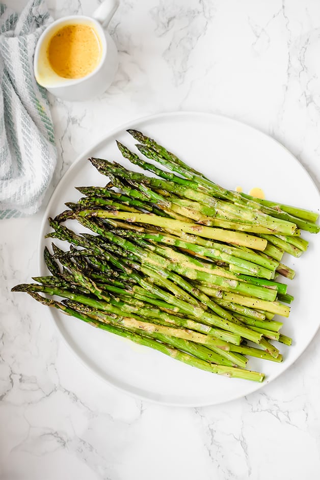 A white plate filled with roasted asparagus.
