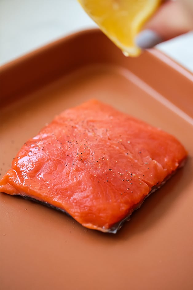 A sheet pan with a fiet of salmon on it before cooking.