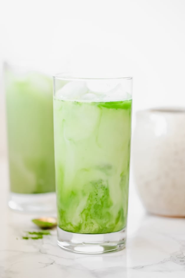 Two glasses filled with iced matcha lattes.