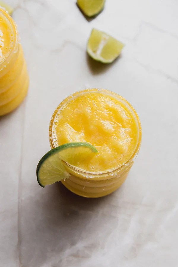 Lime slice on a glass of frozen mango margarita mocktail with a salt rim.