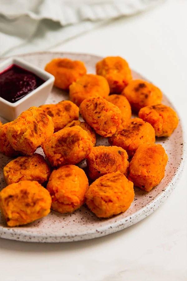 Plate of sweet potato tater tots with a bowl of dip.