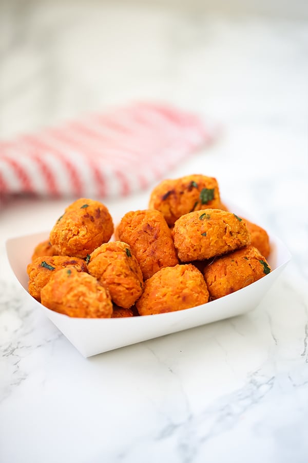 A white paper container filled with sweet potato tater tots.