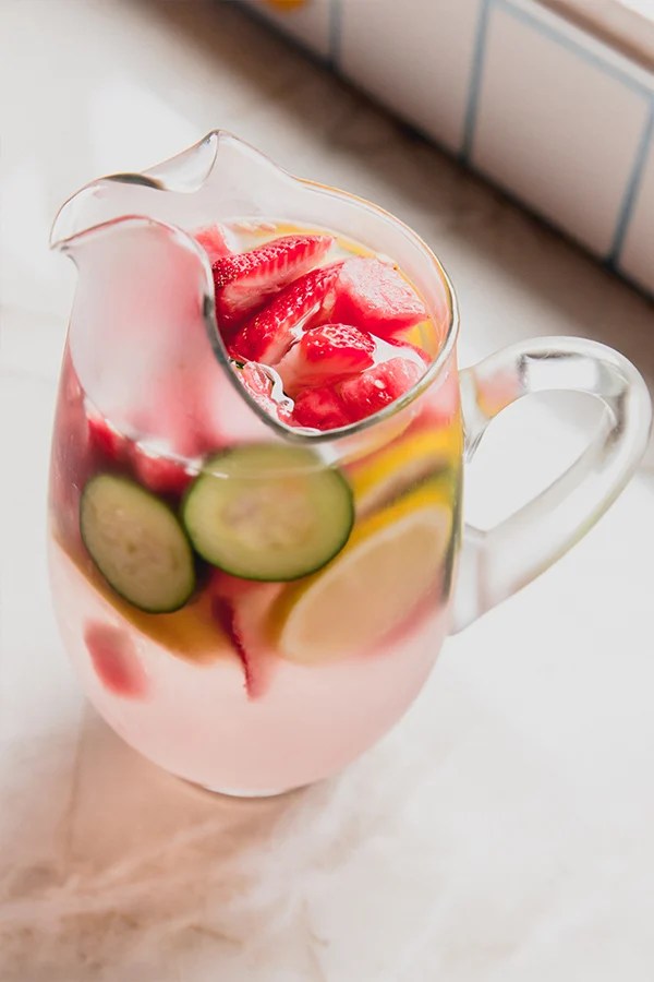 Ginger infused water and fruit in a glass pitcher.