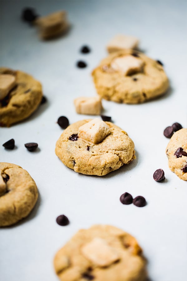 Five s\'mores cookies sitting on a counter with chocolate chips around them.