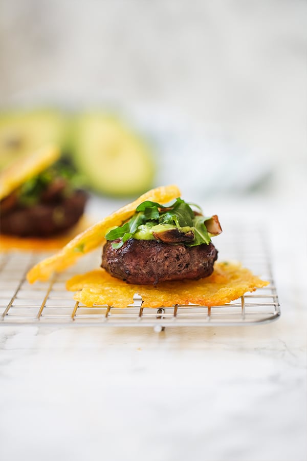 A tostone slider topped with avocado and greens on a wire rack.