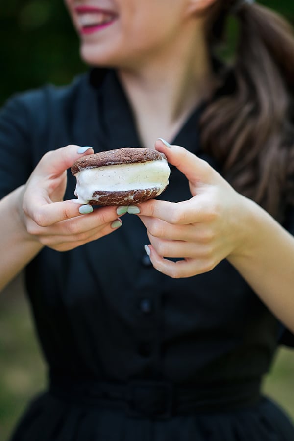A person holding out a ice cream sandwich in their hand.