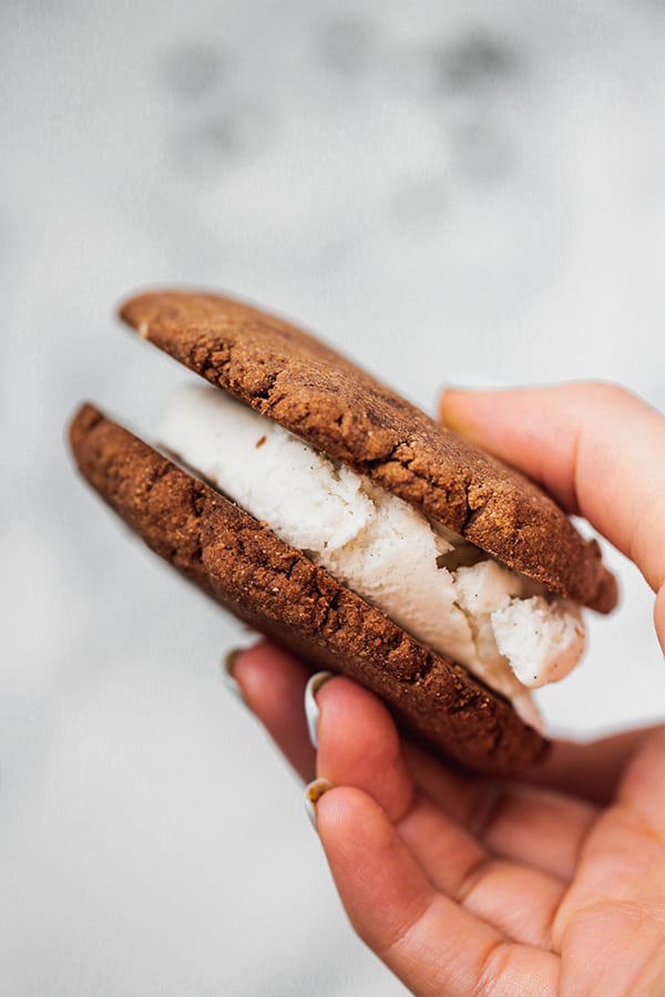 A hand holding a homemade ice cream sandwich in it.