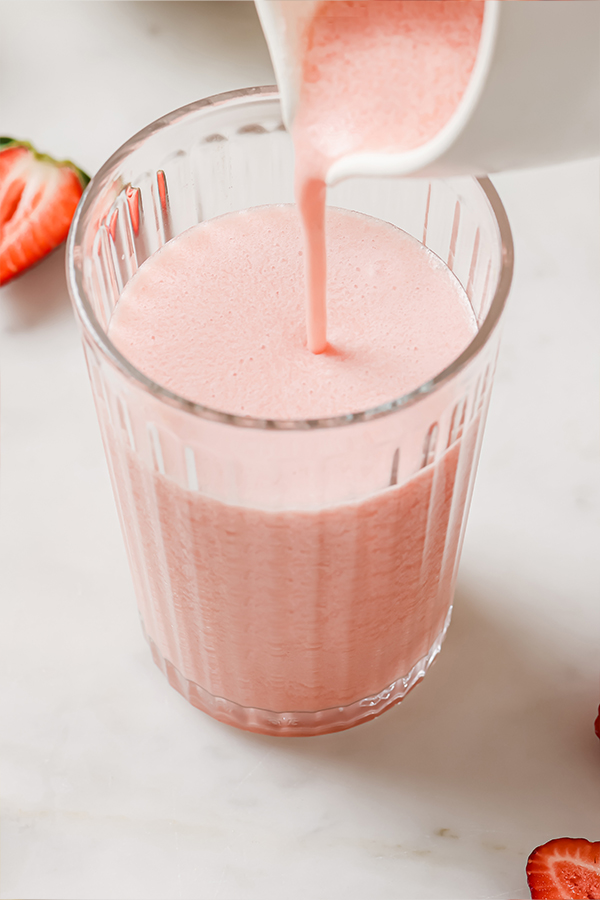 Creamy frozen pink lemonade pouring into a glass.