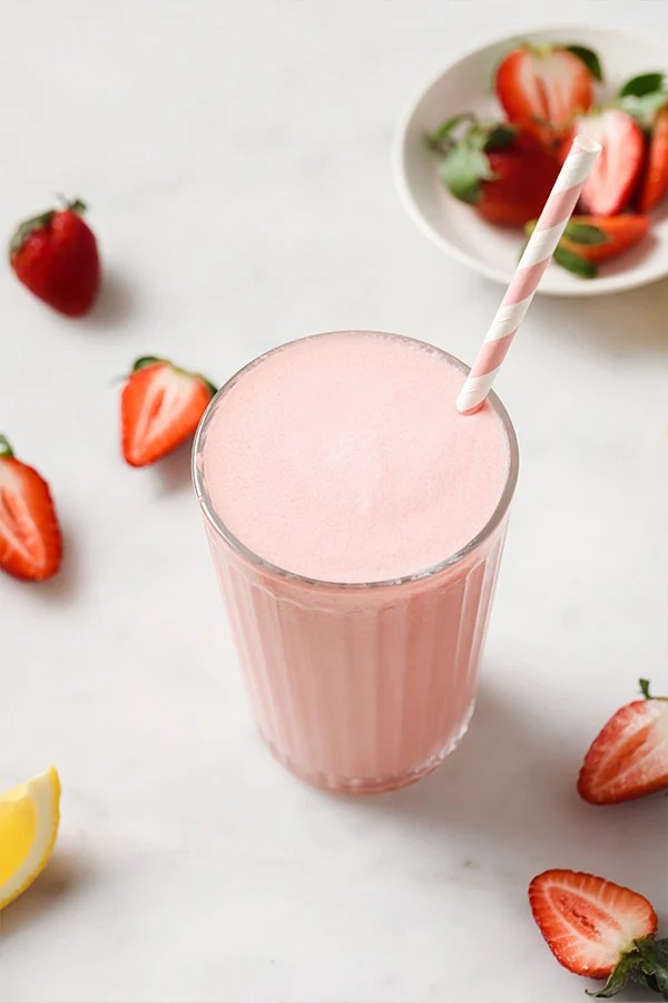 Straw in a tall glass of creamy frozen pink lemonade.