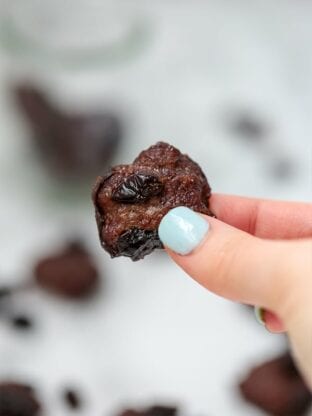A hand with blue nails holding a beef jerky bite.