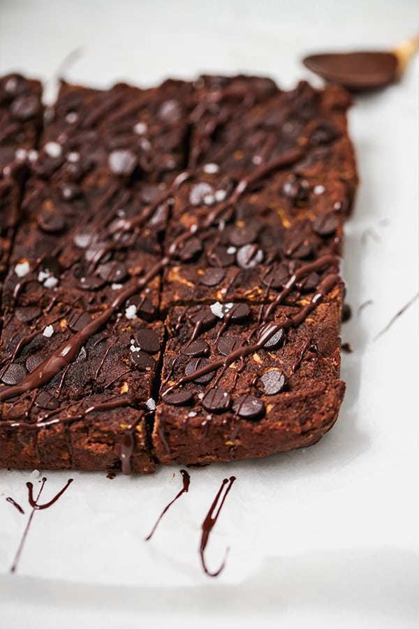 A pan of zucchini brownies cut into squares and sitting on a white counter.