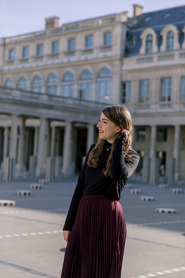 Food blogger Michelle Hoover, a brunette woman with a black shirt and purple skirt in Paris in a courtyard