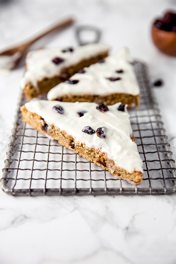 A wire rack topped with three pieces of cranberry bliss bars.