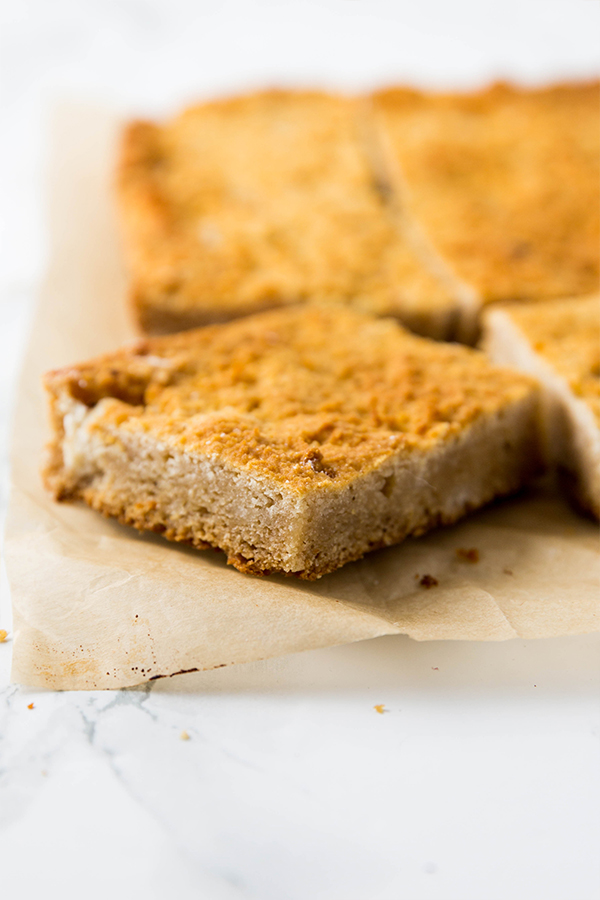 A slice of paleo cornbread being taken out from a pan of cornbread.