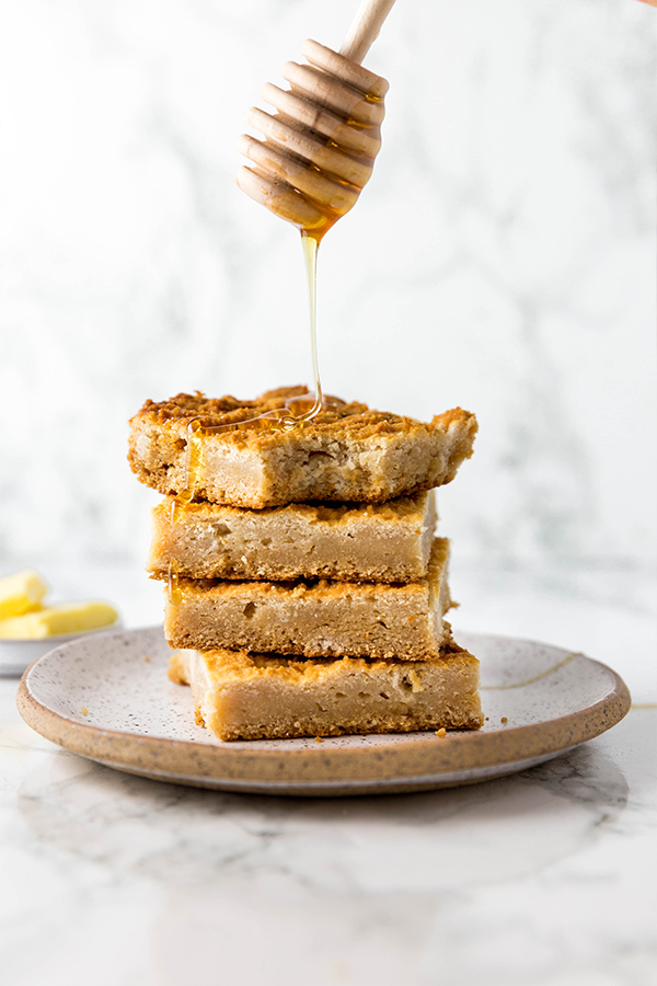A plate with four slices of grain free paleo cornbread with honey being drizzled over it.