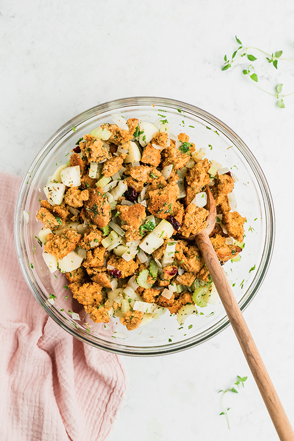 A mixing bowl with ingredients for cornbread stuffing.