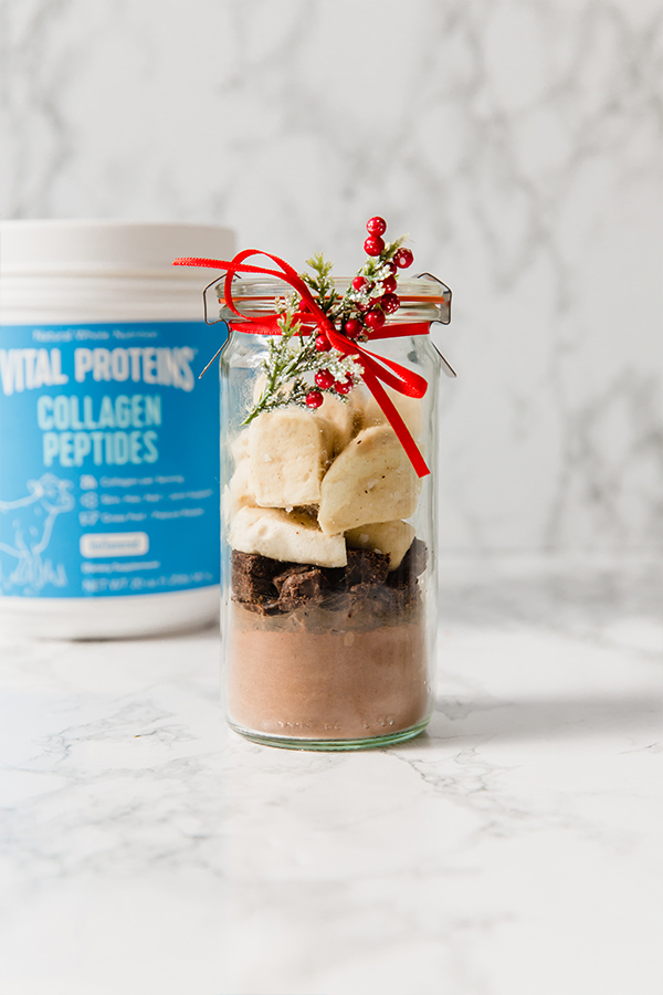 A glass jar with DIY collagen hot cocoa mix with a bow around it.