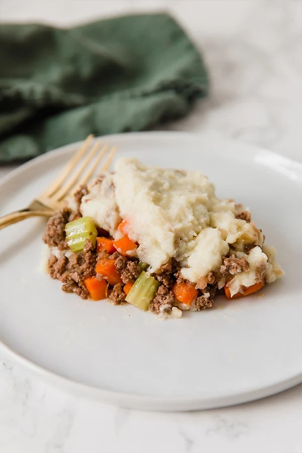 A plate with a serving of cauliflower shepherd\'s pie with a fork next to it.